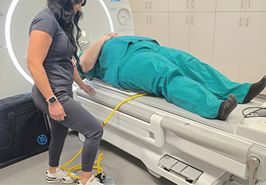 Technologist preparing a patient for KyphoWedge positioning on an MRI table