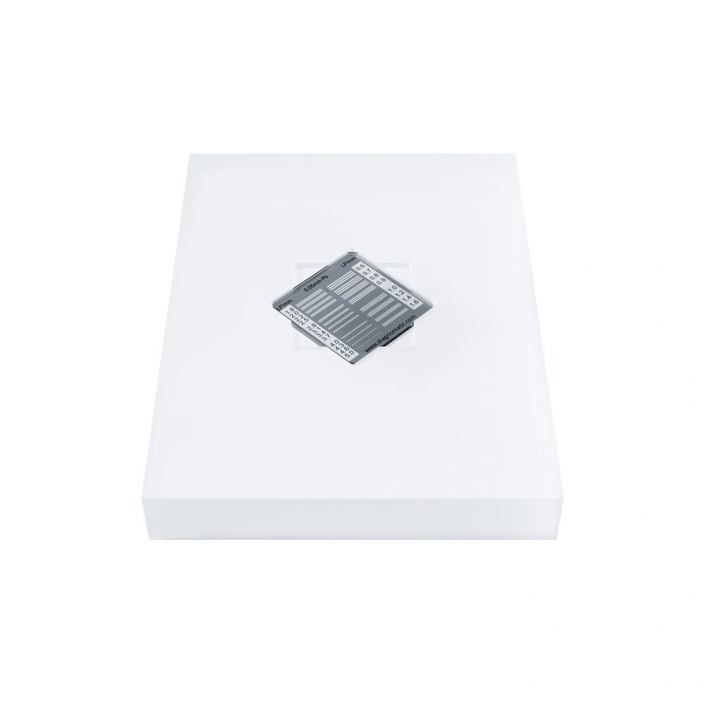 A rectangular block made of sanded transparent plastic with a square hole in the middle for inserting a resolution plate.